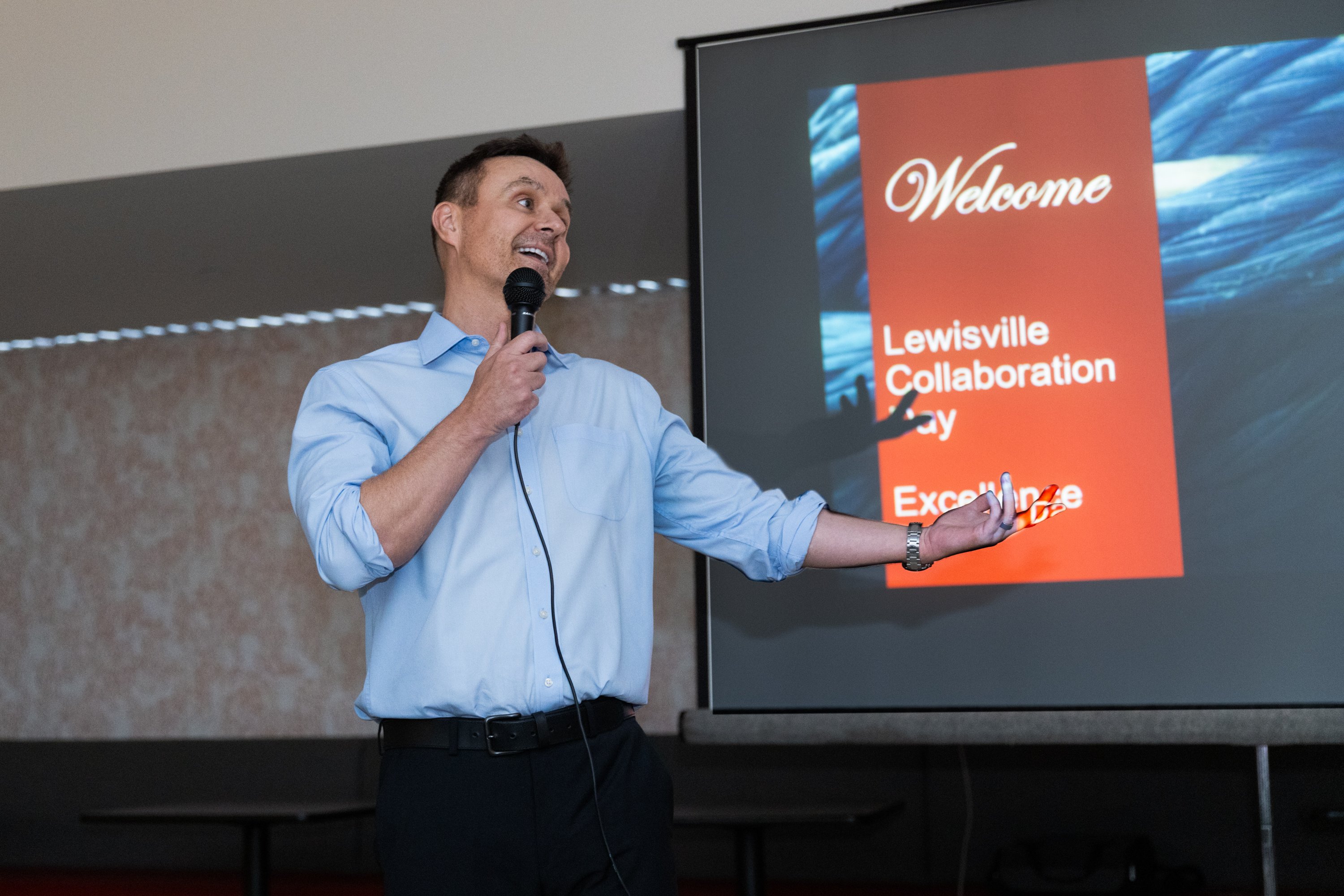 Craig Torrance, MCS. CEO, speaking into a microphone with a slideshow in the background, addressing the audience before presenting.