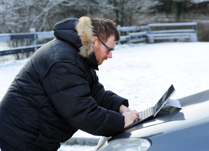 Man using tablet on the car in snowy landscape