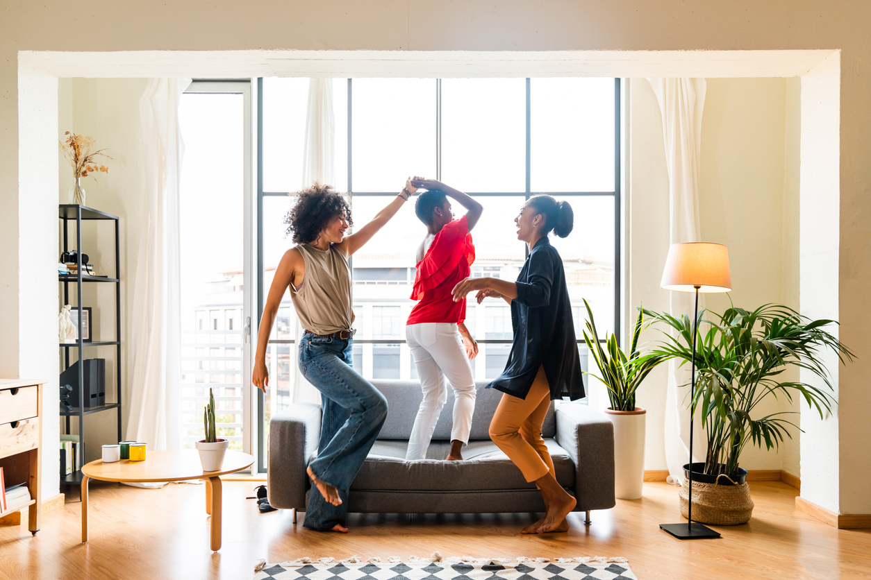 Three residents dancing in a well-lit apartment living room