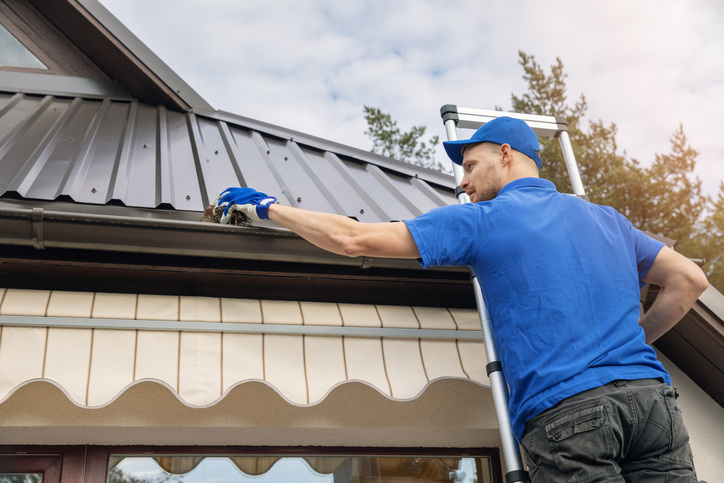 man cleaning home gutters in fall