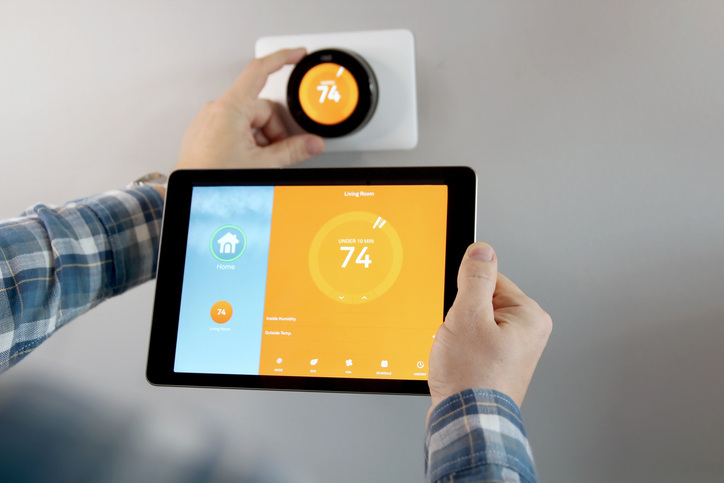 man adjusting smart thermostat with tablet